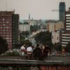 A group of people sitting on a rooftop with a cityscape view at dusk, urban atmosphere.