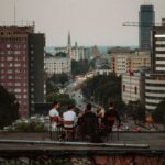 A group of people sitting on a rooftop with a cityscape view at dusk, urban atmosphere.