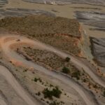 Aerial view of a winding road through Xinjiang's desert landscape with unique geological formations.