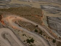 Aerial view of a winding road through Xinjiang's desert landscape with unique geological formations.