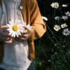 A child gently holds daisies in a garden, evoking a sense of innocence and nature.