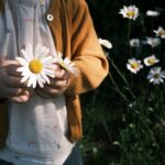 A child gently holds daisies in a garden, evoking a sense of innocence and nature.