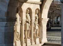 Stone statues at Fisherman's Bastion in Budapest, captured in early morning light, showcasing arches and shadow play.
