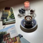 A cozy setup featuring Turkish coffee, a book, and a candle, creating a relaxing ambiance.