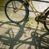 A yellow bicycle casting shadows on a cobblestone path by an Amsterdam canal.
