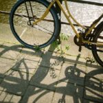 A yellow bicycle casting shadows on a cobblestone path by an Amsterdam canal.