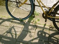 A yellow bicycle casting shadows on a cobblestone path by an Amsterdam canal.