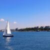 A serene sailboat glides along the Bosphorus near Istanbul, set against a clear blue sky and urban skyline.