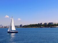 A serene sailboat glides along the Bosphorus near Istanbul, set against a clear blue sky and urban skyline.