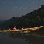 Two people with dogs travel on a wooden canoe in the Amazon River, Peru.