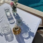 Elegant poolside setup with a teapot, glasses, and flower vase on a sunny day in Montenegro.