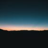 Dark mountain silhouettes against a colorful twilight sky.