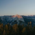 Half dome mountain at sunset with pine trees.