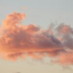 Pink and orange clouds against a pale sky at sunset.