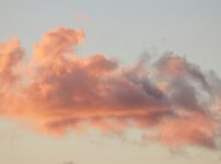 Pink and orange clouds against a pale sky at sunset.