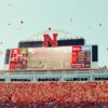 Fans celebrate at a football stadium with scoreboards.