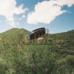 A rustic structure nestled in green, rolling hills.