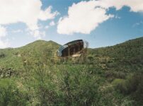 A rustic structure nestled in green, rolling hills.