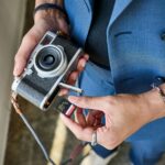 Hands inserting an sd card into a retro camera.