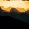Silhouetted mountain ranges at golden hour sunset.