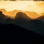 Silhouetted mountain ranges at golden hour sunset.