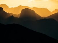 Silhouetted mountain ranges at golden hour sunset.